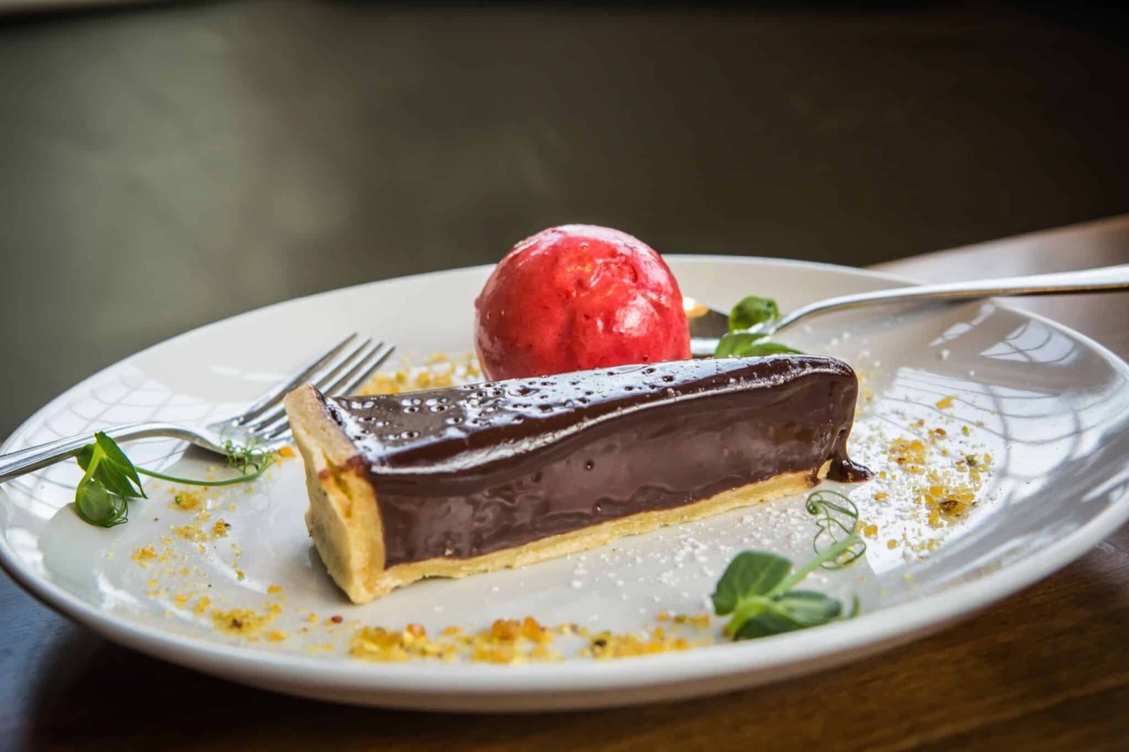 A slice of chocolate tart with a raspberry sorbet