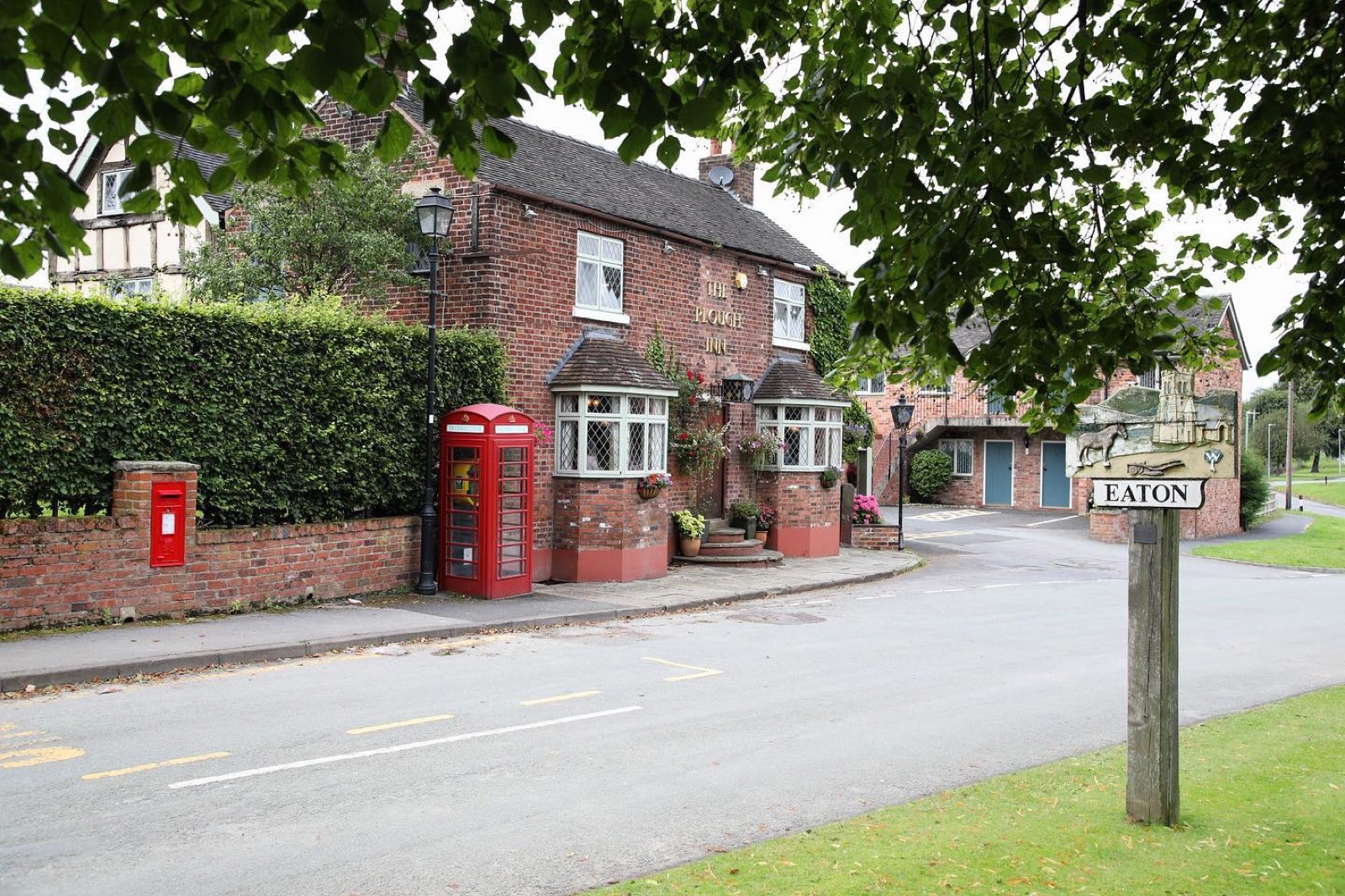 The Plough Inn beside the road into Eaton, with the village sign
